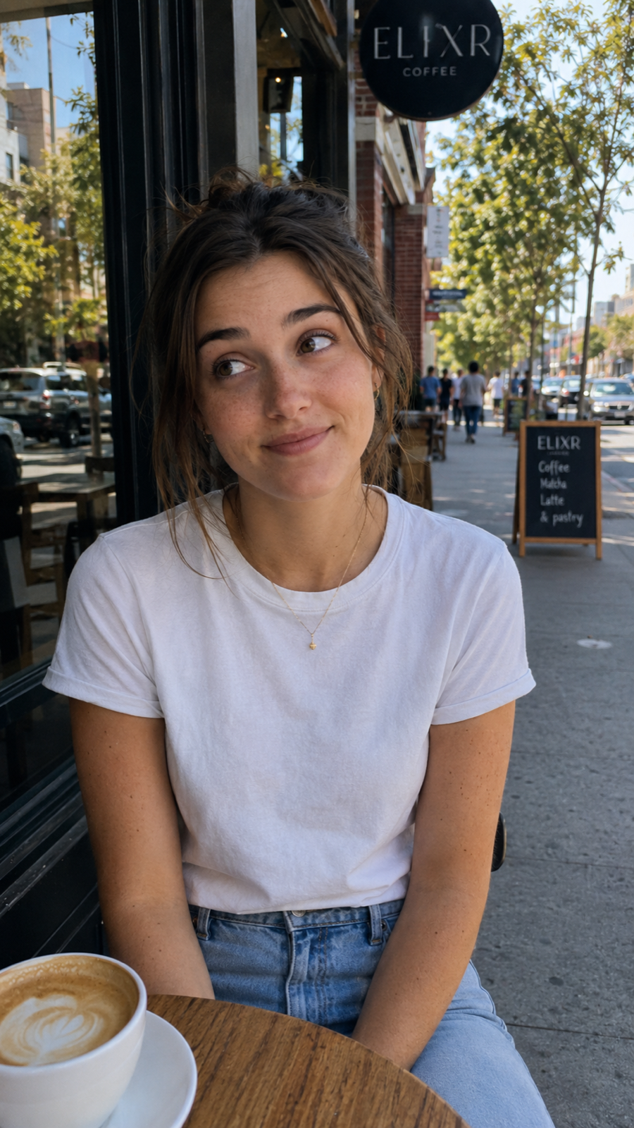 A person wearing a small gold necklace at a café